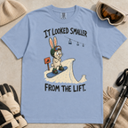 Flat lay of a washed denim blue t-shirt with a humorous snowboarding design showing a worried rabbit facing an unexpectedly steep jump.