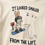 Close-up of an ivory white t-shirt featuring a nervous rabbit snowboarder at the edge of a large snow jump, with “It Looked Smaller From the Lift.” text.