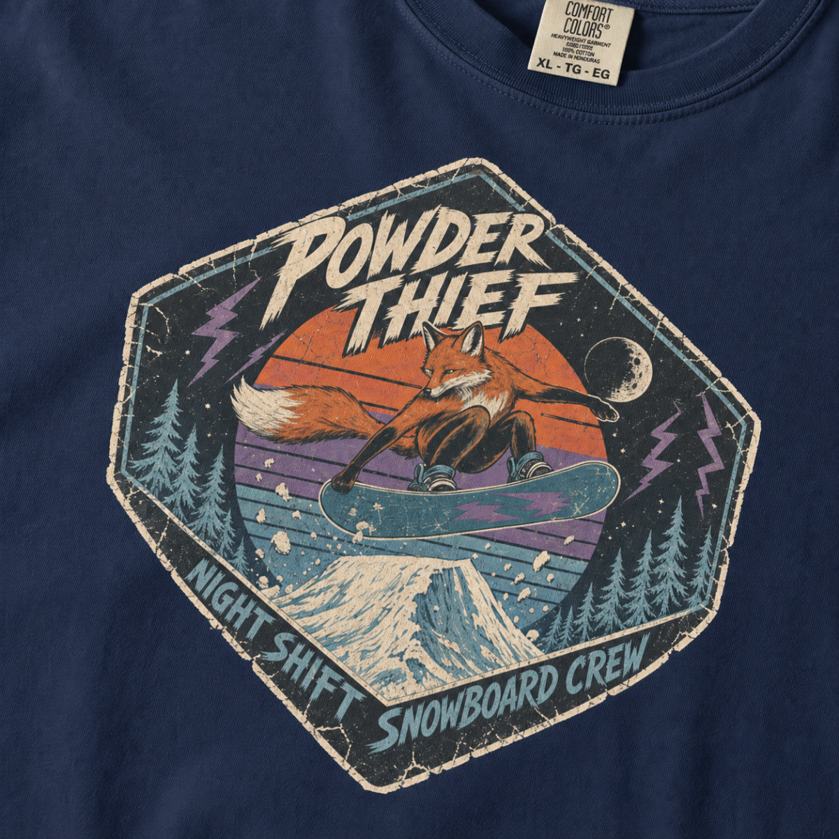 Close-up of a navy blue t-shirt featuring a vintage fox snowboarding at night with “Powder Thief – Night Shift Snowboard Crew” text.