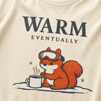 Close-up of an ivory white t-shirt design showing a ski-goggle-wearing squirrel beside a hot drink under “Warm Eventually” text.