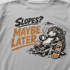 Close-up of a reclining hedgehog holding a hot drink beside a snowboard with “Slopes? Maybe Later.” lettering.