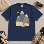 Navy t-shirt featuring a minimalist alpine scene with three snow-capped mountains, pine trees, a golden sun and a small skiing animal.