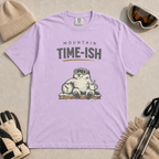Orchid purple t-shirt featuring a relaxed marmot in ski goggles holding a clock and steaming mug beneath the words “Mountain Time-ish.”