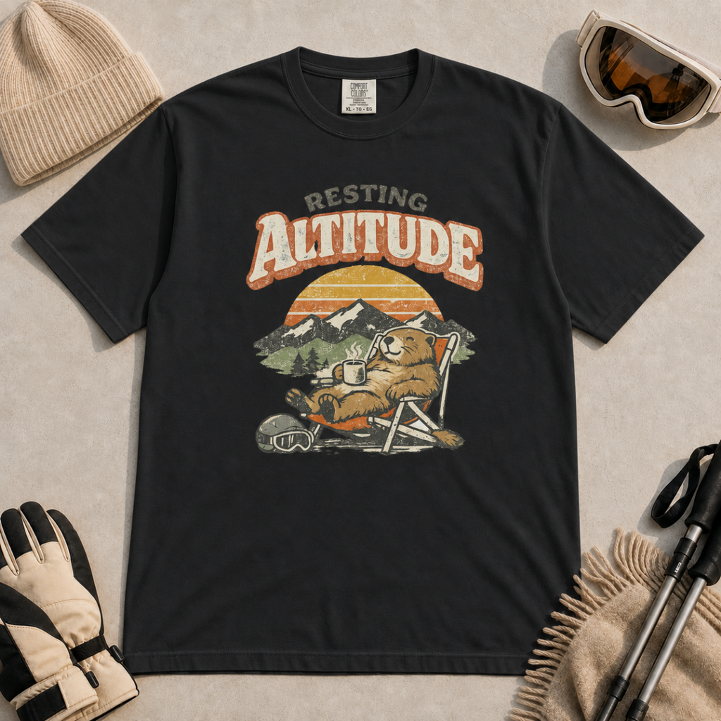 Black t-shirt featuring a marmot resting in a chair with a mug, ski helmet and goggles beneath “Resting Altitude” text.