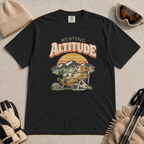 Black t-shirt featuring a marmot resting in a chair with a mug, ski helmet and goggles beneath “Resting Altitude” text.