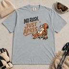 Granite gray t-shirt featuring a relaxed red squirrel in ski goggles sitting in a chair with a steaming mug and ski helmet, beside the words “No Rush, Just Après.”