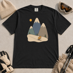 Black t-shirt featuring a minimalist alpine scene with three snow-capped mountains, pine trees, a golden sun and a small skiing animal.
