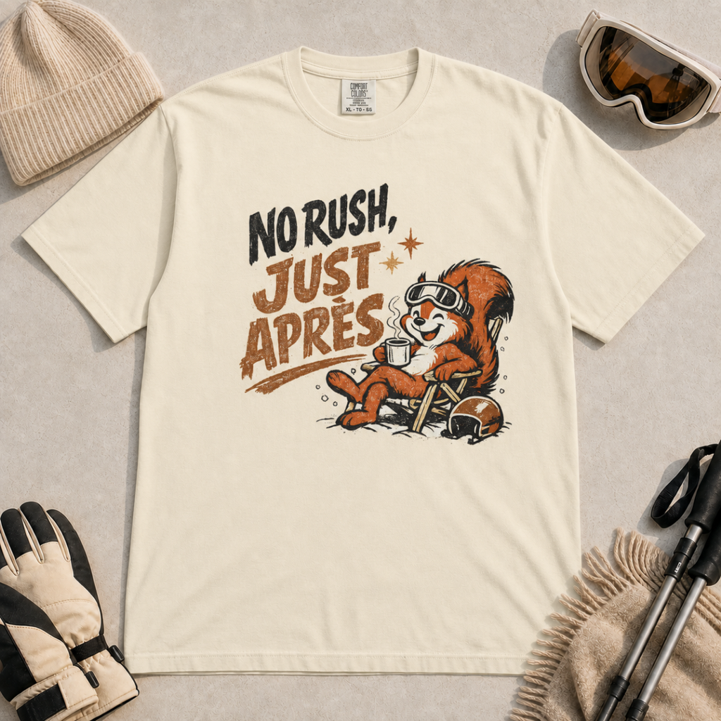 Ivory white t-shirt featuring a relaxed red squirrel in ski goggles sitting in a chair with a steaming mug and ski helmet, beside the words “No Rush, Just Après.”