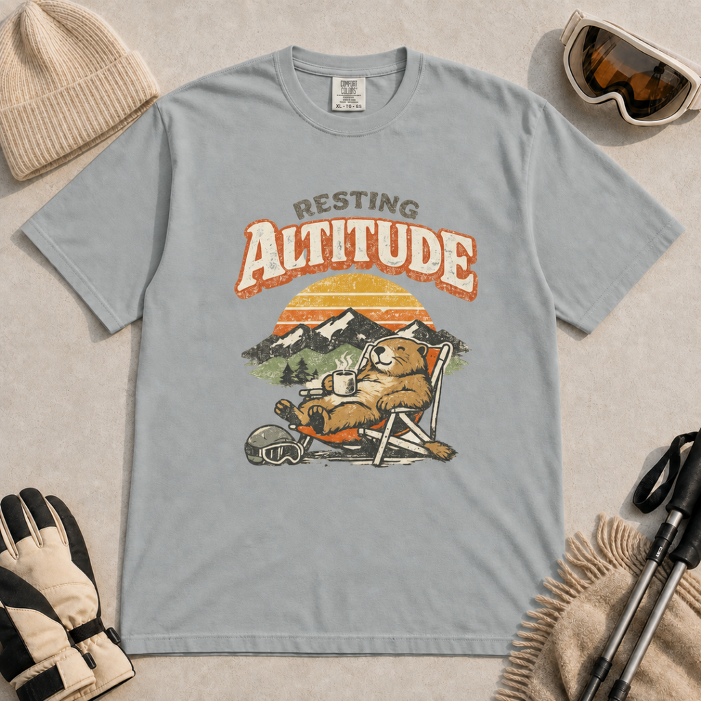 Granite gray t-shirt featuring a marmot resting in a chair with a mug, ski helmet and goggles beneath “Resting Altitude” text.