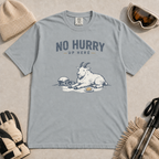 Granite gray t-shirt featuring a mountain goat relaxing in the snow with a helmet, goggles and snack beneath the words “No Hurry Up Here.”