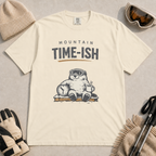 Ivory white t-shirt featuring a relaxed marmot in ski goggles holding a clock and steaming mug beneath the words “Mountain Time-ish.”