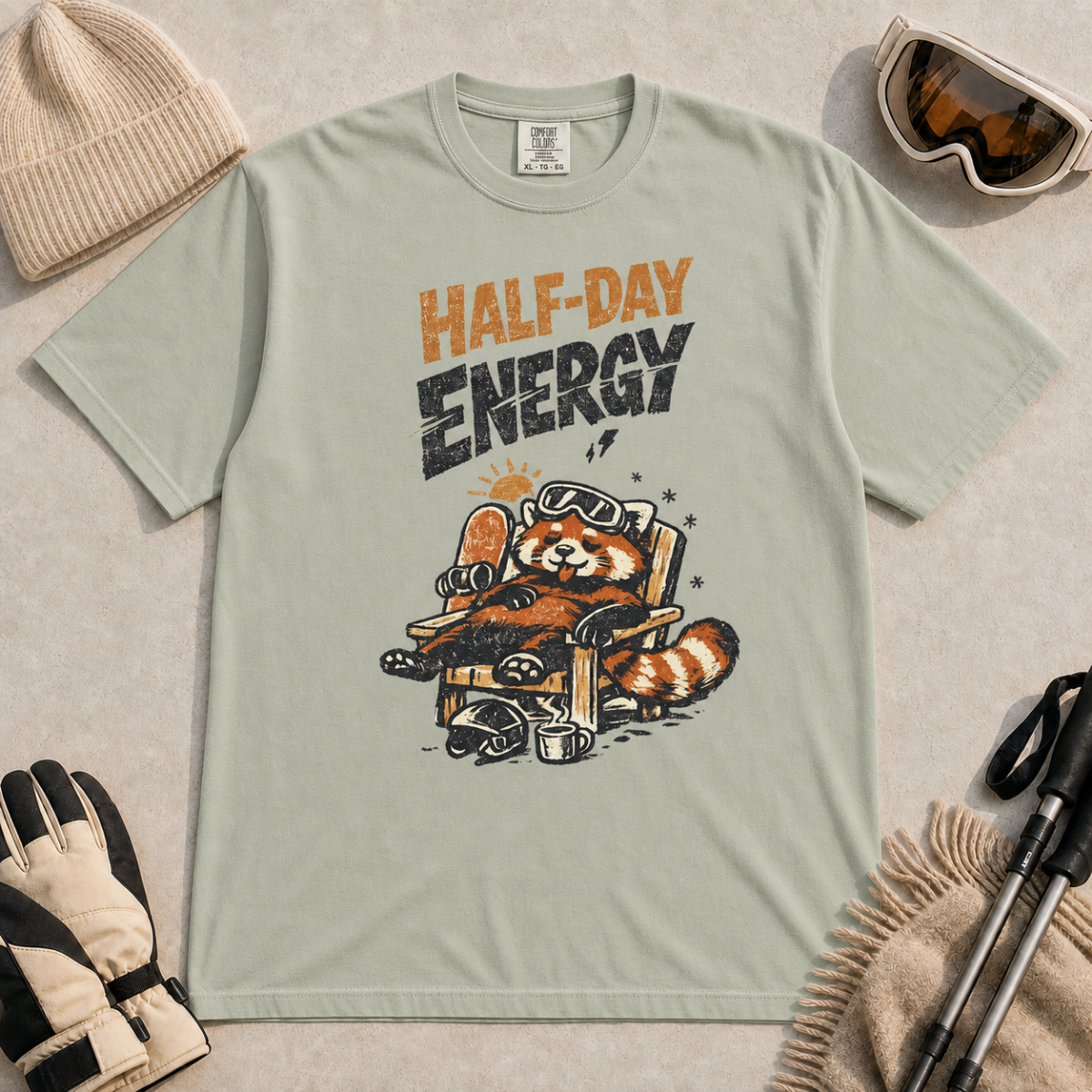 Bay green t-shirt featuring a relaxed red panda in a chair beside a helmet and mug with the phrase “Half-Day Energy.”