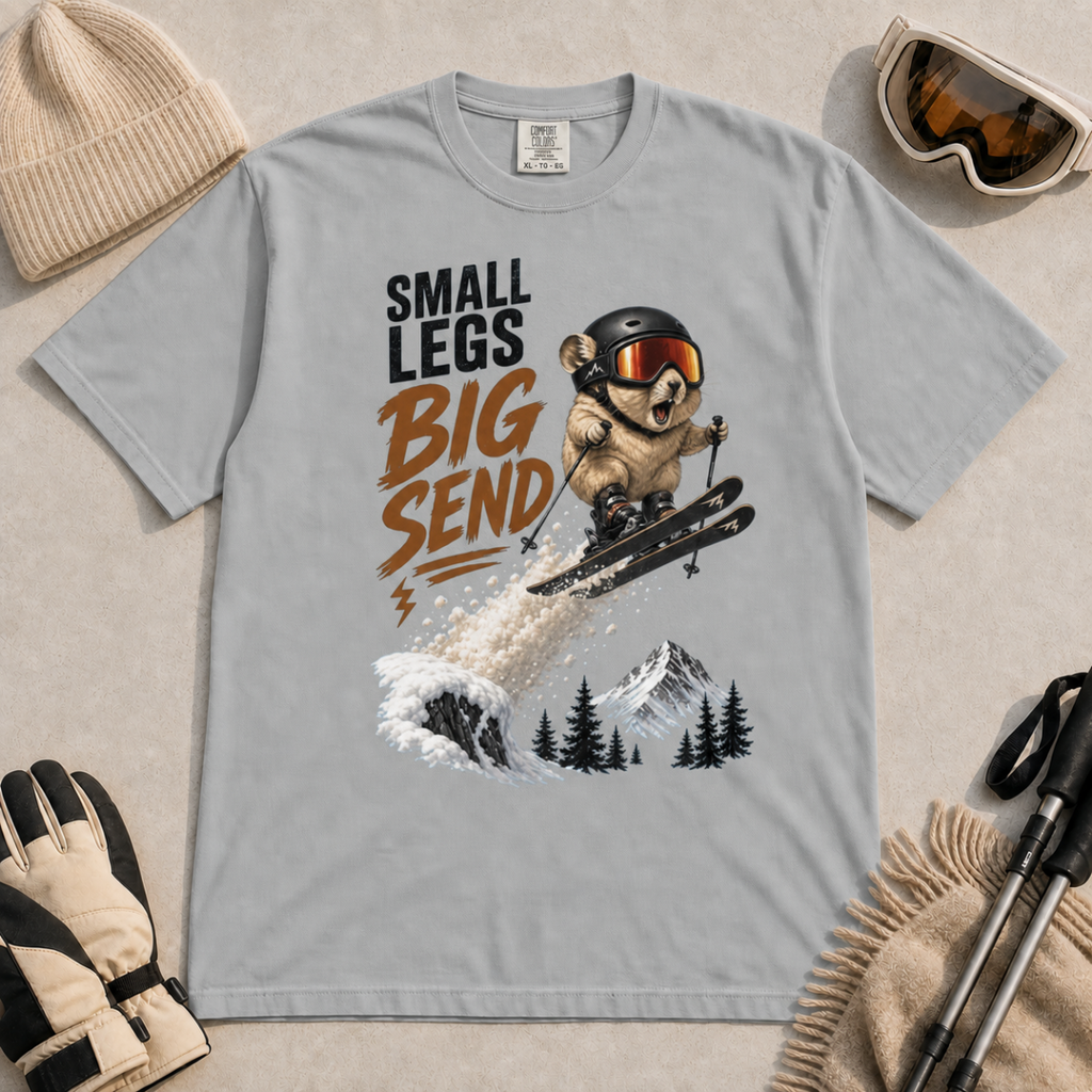 Granite gray t-shirt featuring a helmeted pika launching off a snowy ski jump with the phrase “Small Legs Big Send.”