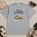 Granite gray t-shirt featuring a relaxed red panda in ski goggles lying beside a snowboard beneath the words “Maybe Later.”