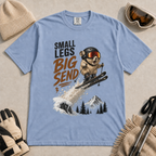 Washed denim blue t-shirt featuring a helmeted pika launching off a snowy ski jump with the phrase “Small Legs Big Send.”