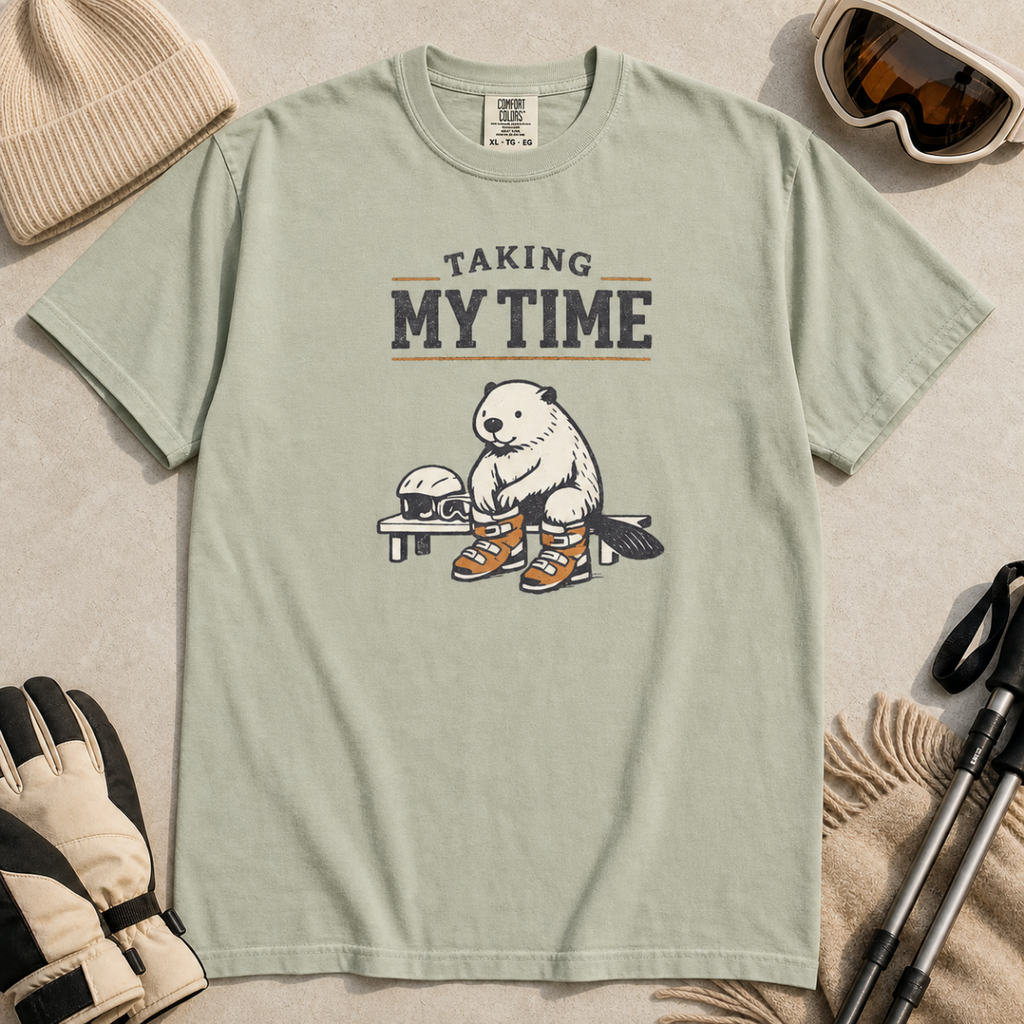 Bay green t-shirt featuring a beaver seated on a bench fastening snowboard boots beneath “Taking My Time” text.
