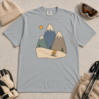 Granite gray t-shirt featuring a minimalist alpine scene with three snow-capped mountains, pine trees, a golden sun and a small skiing animal.