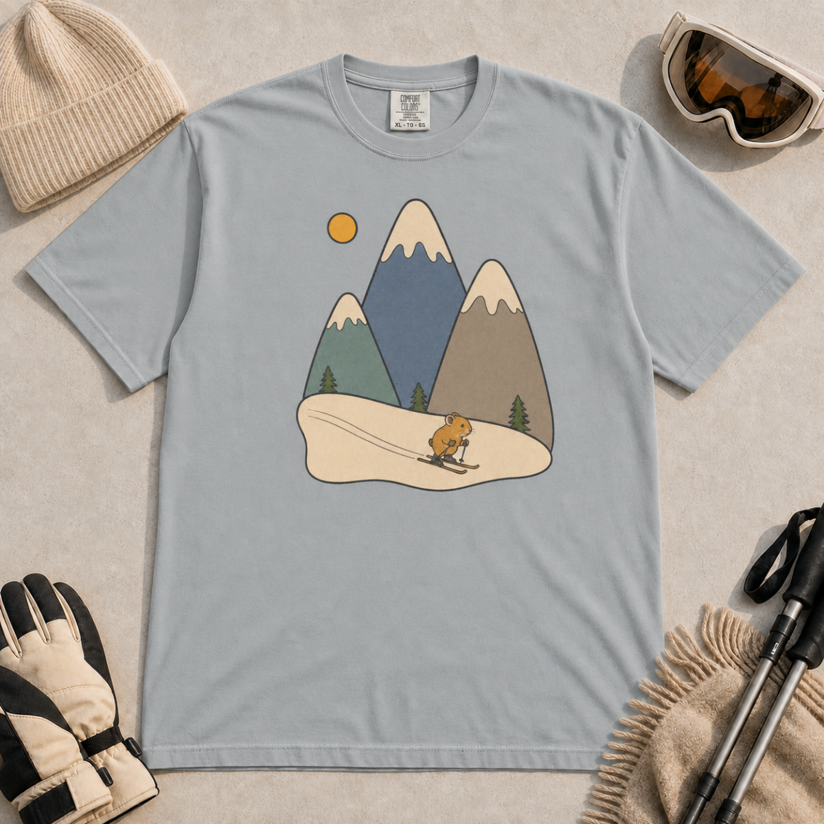 Granite gray t-shirt featuring a minimalist alpine scene with three snow-capped mountains, pine trees, a golden sun and a small skiing animal.