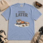 Washed denim blue t-shirt featuring a relaxed red panda in ski goggles lying beside a snowboard beneath the words “Maybe Later.”