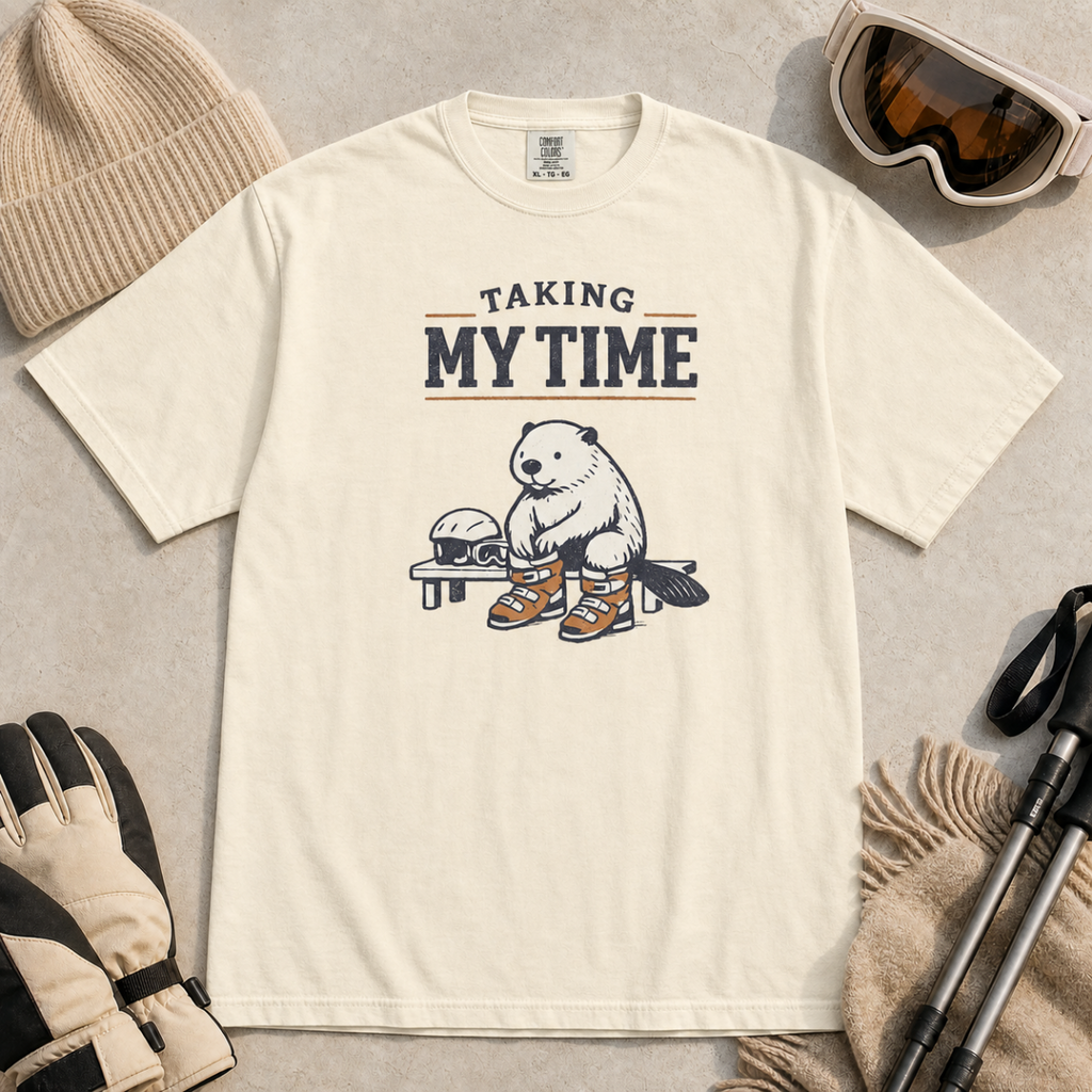 Ivory white t-shirt featuring a beaver seated on a bench fastening snowboard boots beneath “Taking My Time” text.