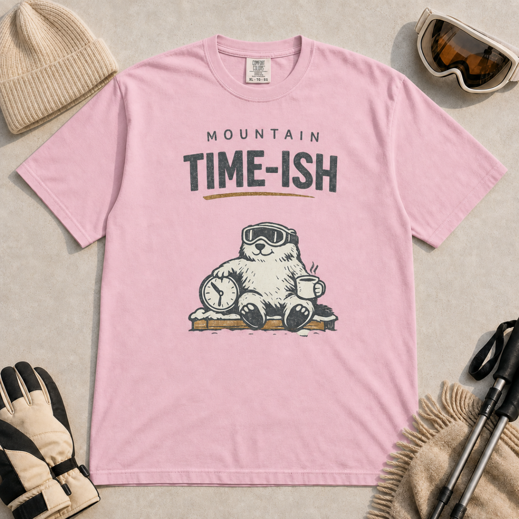 Blossom pink t-shirt featuring a relaxed marmot in ski goggles holding a clock and steaming mug beneath the words “Mountain Time-ish.”