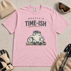 Blossom pink t-shirt featuring a relaxed marmot in ski goggles holding a clock and steaming mug beneath the words “Mountain Time-ish.”