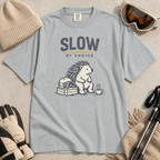 Granite gray t-shirt featuring a seated hedgehog beside ski goggles and a hot drink beneath “Slow by Choice” text.