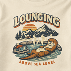 Close-up of a vintage otter hot spring design with snowy mountains, a sunset and the words “Lounging Above Sea Level.”