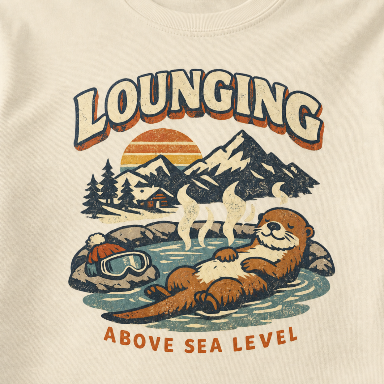 Close-up of a vintage otter hot spring design with snowy mountains, a sunset and the words “Lounging Above Sea Level.”