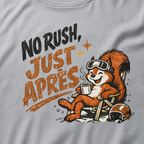 Close-up of a granite gray t-shirt featuring a relaxed red squirrel in ski goggles reclining in a chair with a steaming mug, beside the words “No Rush, Just Après.”