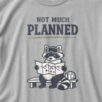 Close-up of a granite gray t-shirt featuring a raccoon in ski goggles holding a mountain map beside a backpack, with the words “Not Much Planned.”