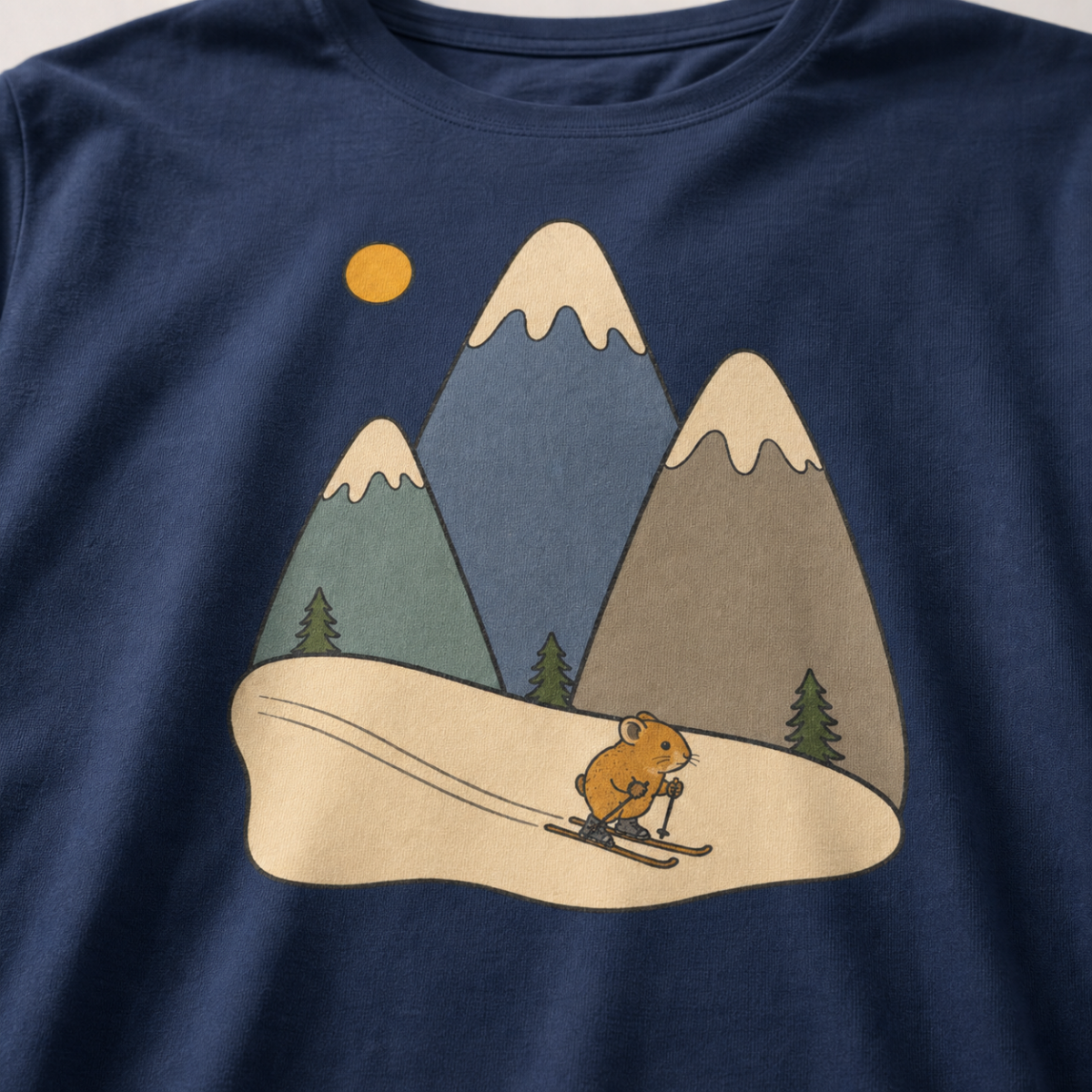 Close-up of a navy blue t-shirt featuring three muted snow-capped mountains, pine trees, a golden sun and a tiny animal skiing downhill.