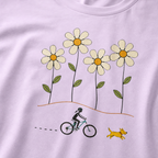 Close-up of a female mountain biker riding beside a yellow dog beneath four large hand-drawn daisies.