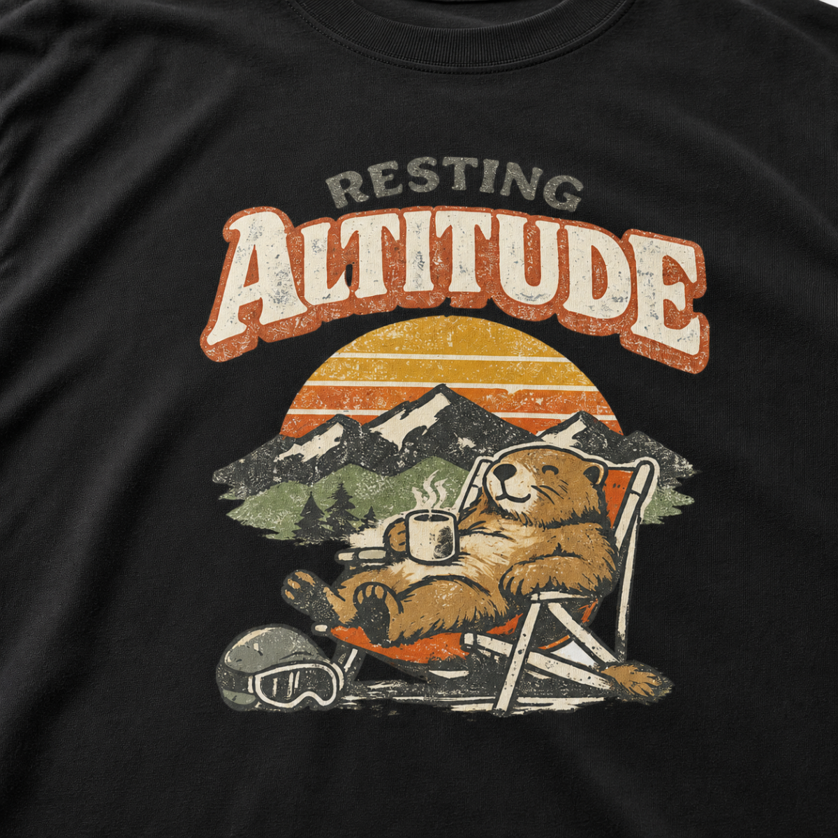 Close-up of a relaxed marmot reclining in a chair with a steaming mug beneath “Resting Altitude” lettering and a mountain sunset.