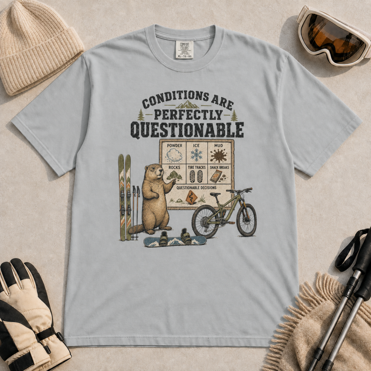 Granite gray t-shirt featuring a marmot with skiing, snowboarding, and mountain biking gear under “Conditions Are Perfectly Questionable” text.