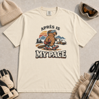Ivory white t-shirt featuring a beaver in ski boots holding a mug beneath the words “Après Is My Pace.”