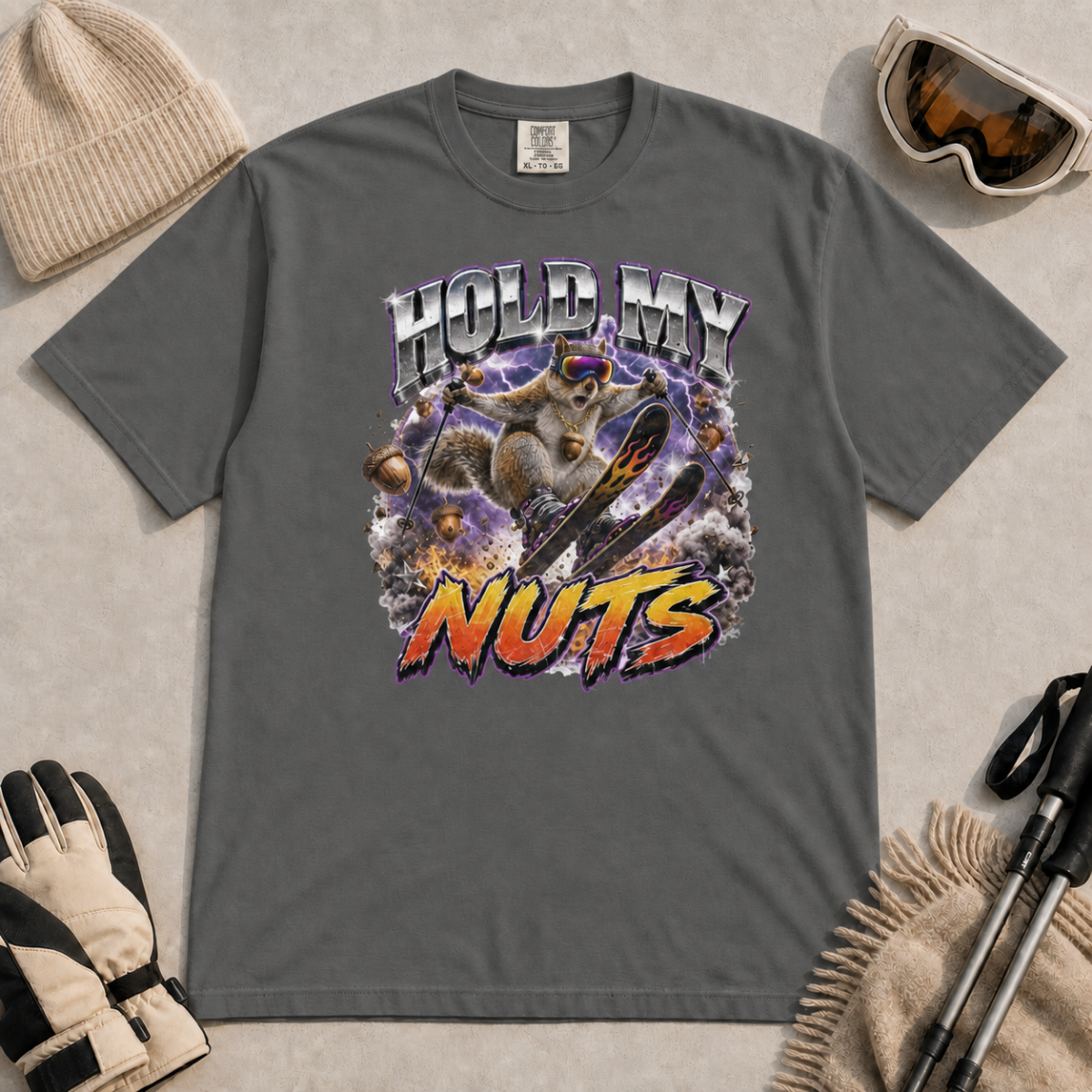 Pepper gray t-shirt featuring a squirrel performing an aerial ski trick beneath the words “Hold My Nuts.”