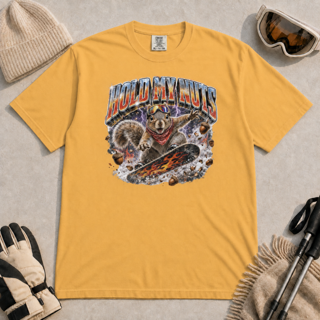 Mustard yellow t-shirt featuring a squirrel snowboarding through flying acorns beneath the words “Hold My Nuts.”