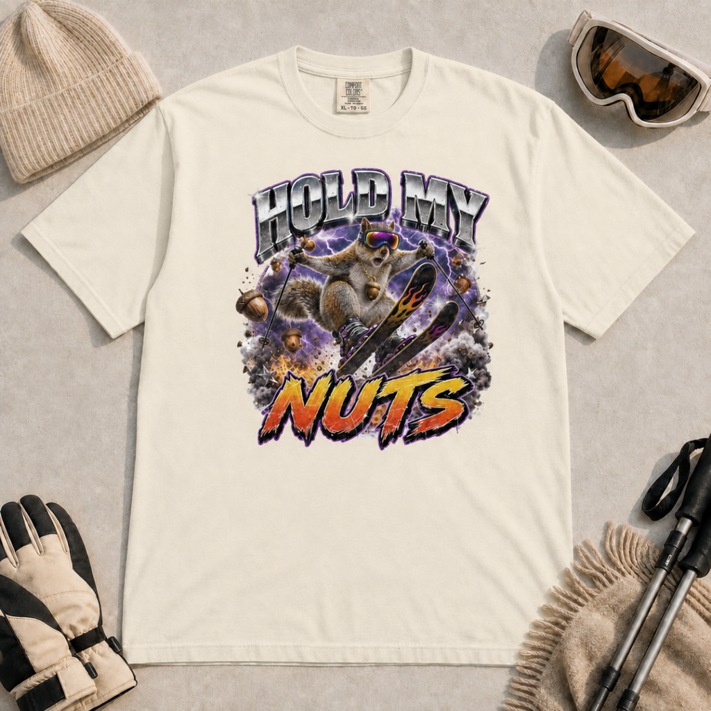 Ivory white t-shirt featuring a squirrel performing an aerial ski trick beneath the words “Hold My Nuts.”