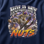 Close-up of a bold squirrel skiing design with purple lightning, flying acorns, and the words “Hold My Nuts” on a charcoal gray t-shirt.