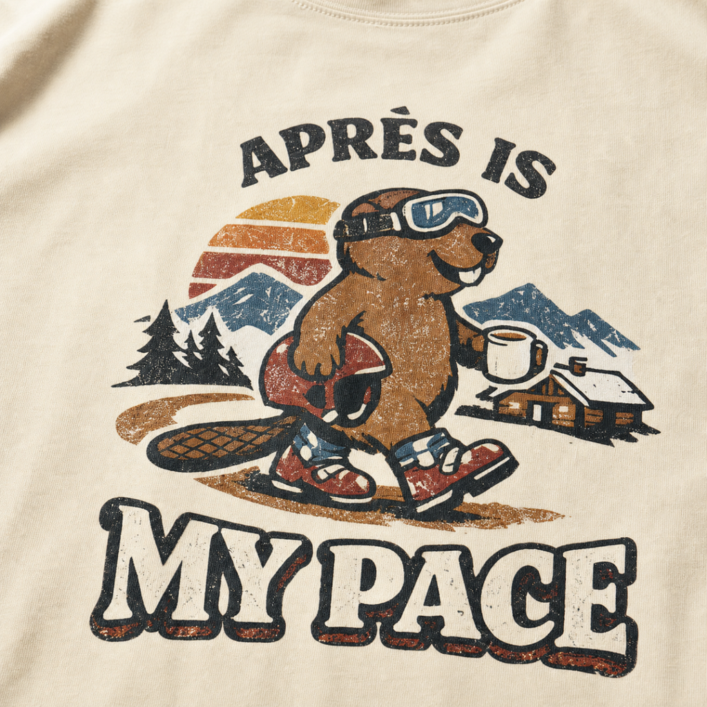 Close-up of a vintage beaver après-ski design with mountains, a cabin, and the words “Après Is My Pace” on an ivory white t-shirt.