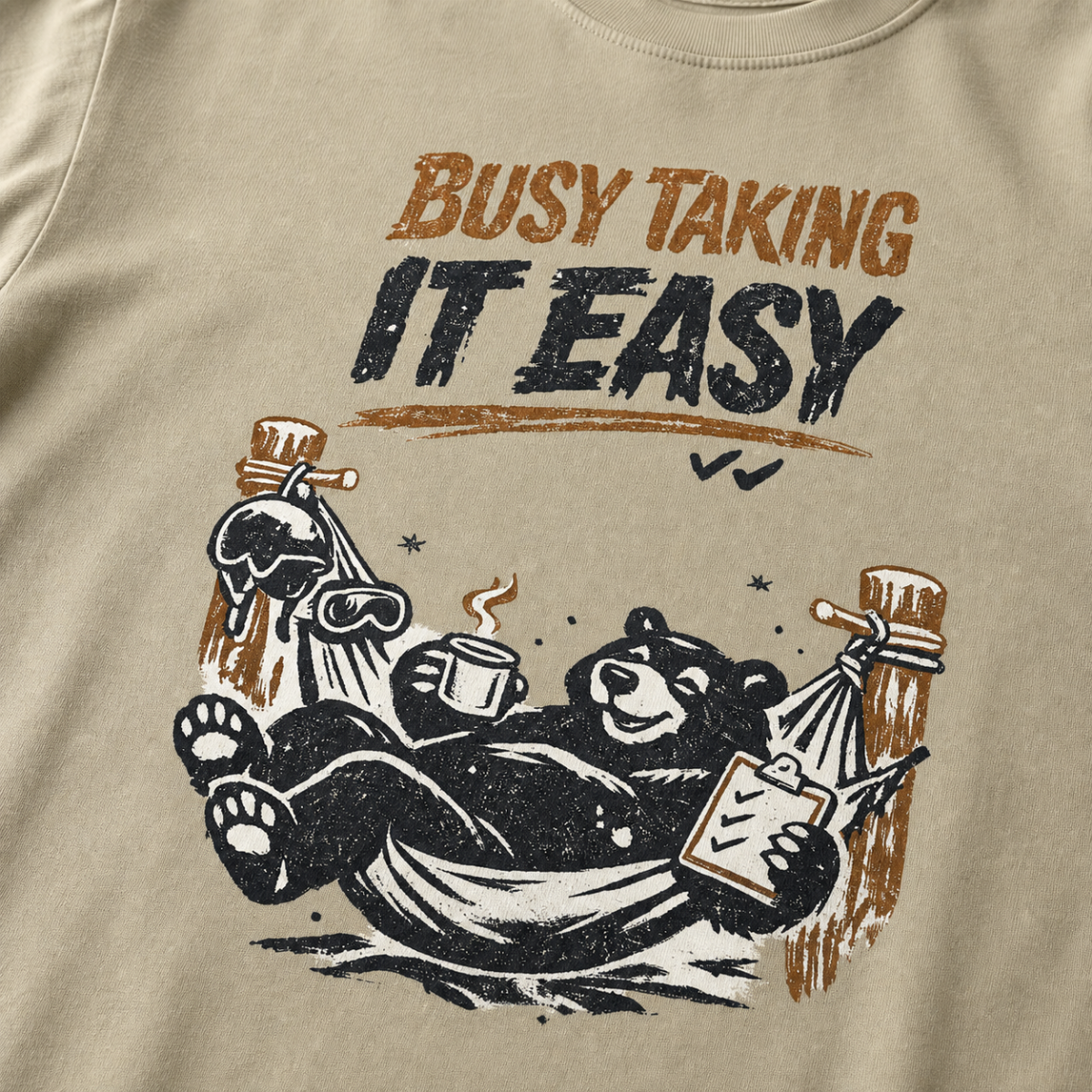 Close-up of a black bear relaxing in a ski-lodge hammock with a hot drink and checklist beneath the words “Busy Taking It Easy.”