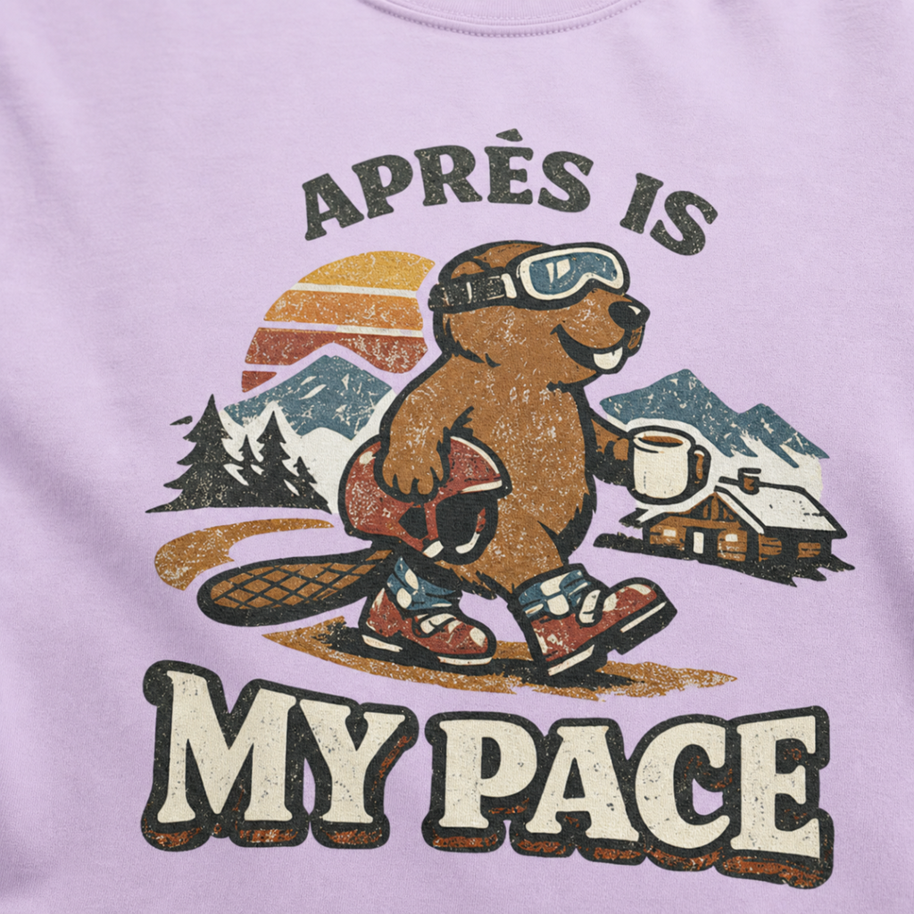Close-up of a vintage beaver après-ski design with mountains, a cabin, and the words “Après Is My Pace” on an orchid purple t-shirt.