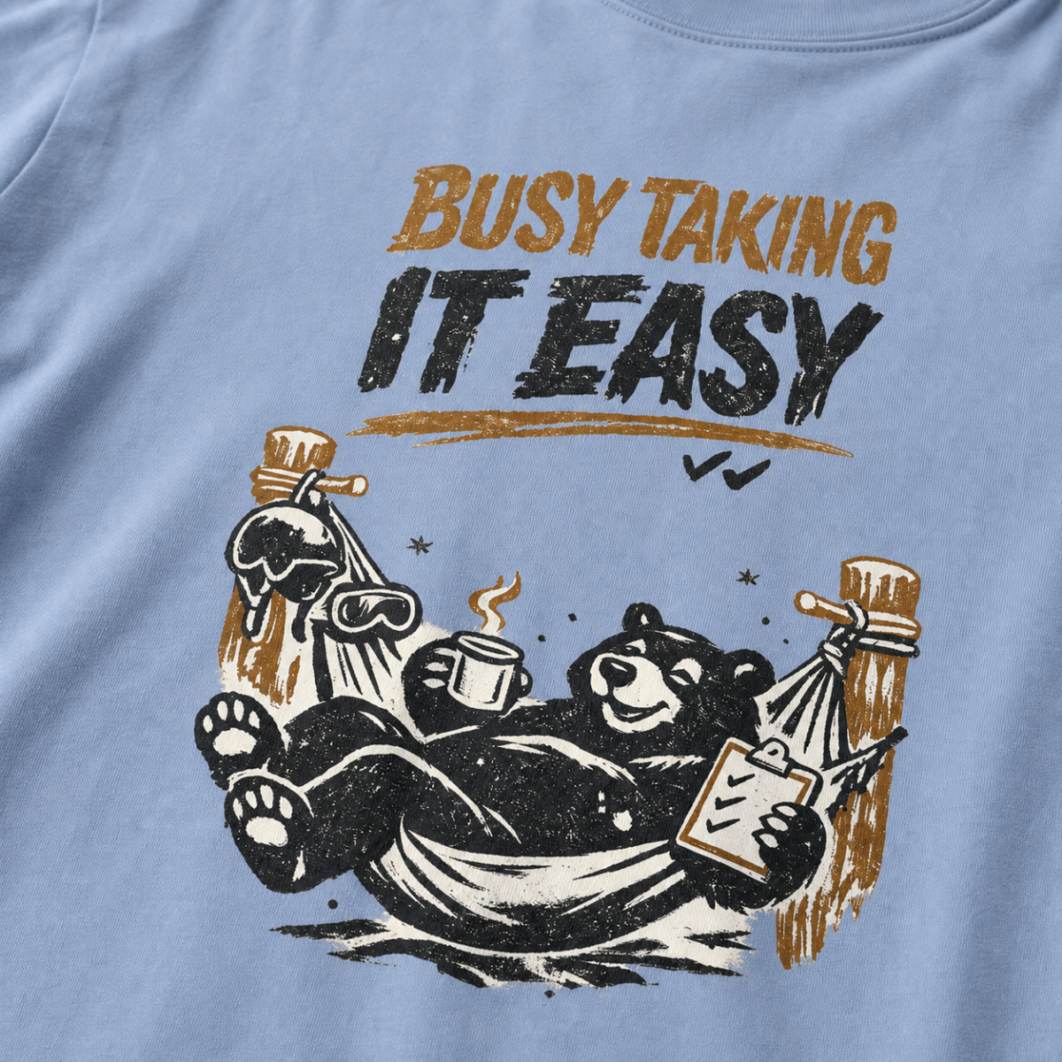 Close-up of a black bear relaxing in a ski-lodge hammock with a hot drink and checklist beneath the words “Busy Taking It Easy.”
