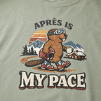 Close-up of a vintage beaver après-ski design with mountains, a cabin, and the words “Après Is My Pace” on a bay green t-shirt.