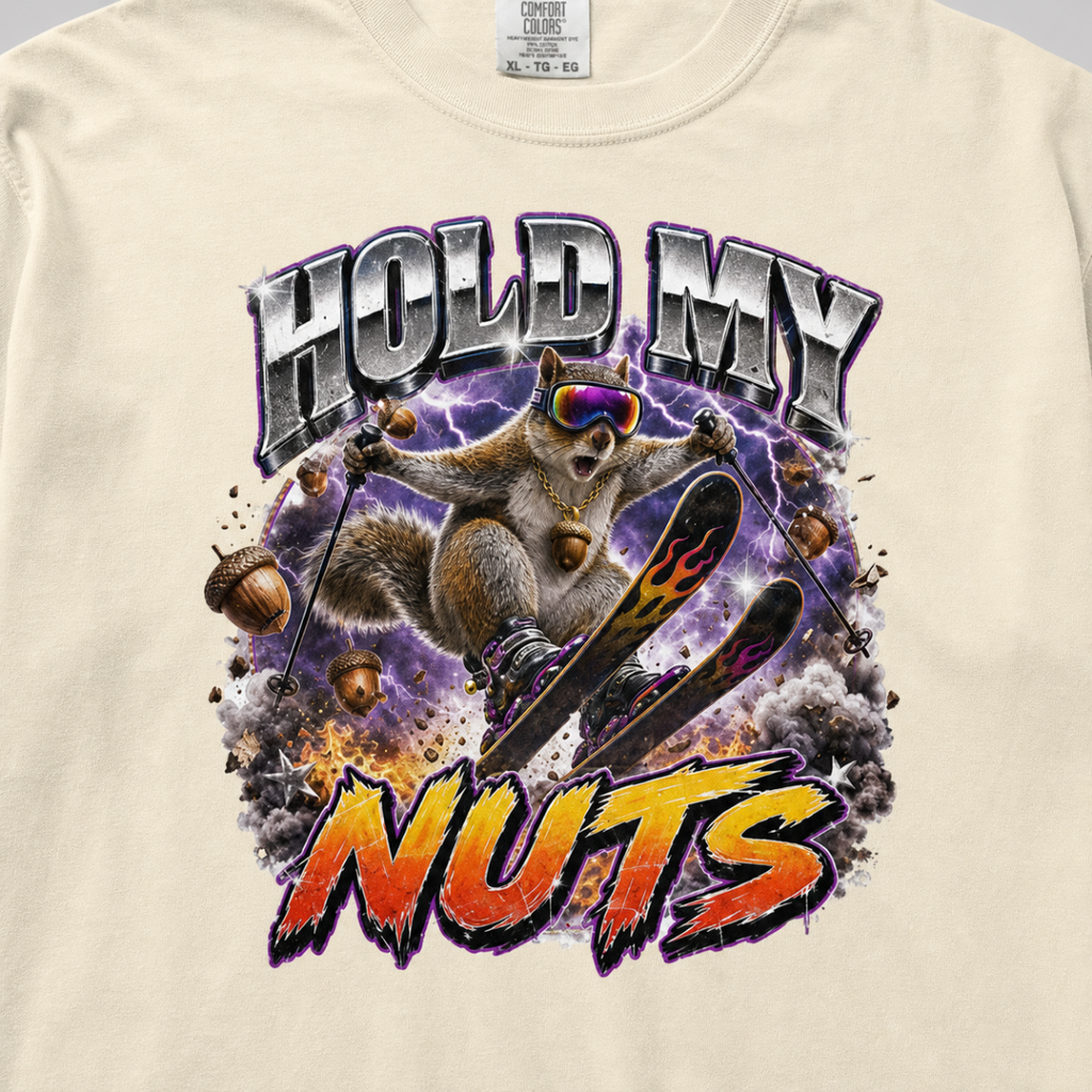 Close-up of a bold squirrel skiing design with purple lightning, flying acorns, and the words “Hold My Nuts” on a charcoal gray t-shirt.
