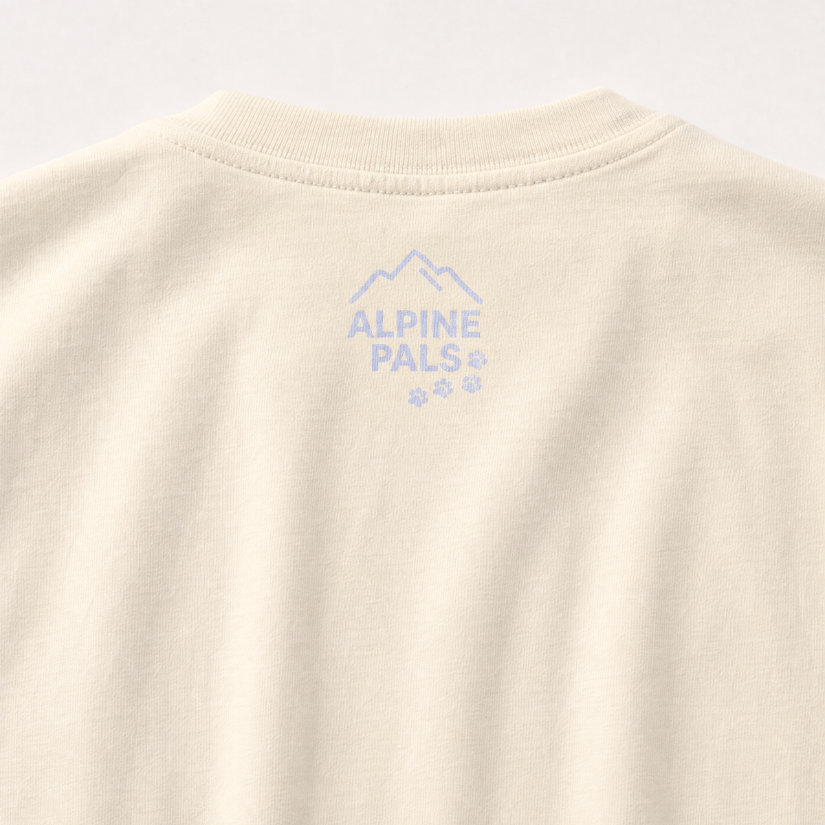 Ivory colored fabric with 'Alpine Pals' logo embroidered on a light gray background