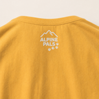 Mustard yellow shirt with 'Alpine Pals' logo on a beige background