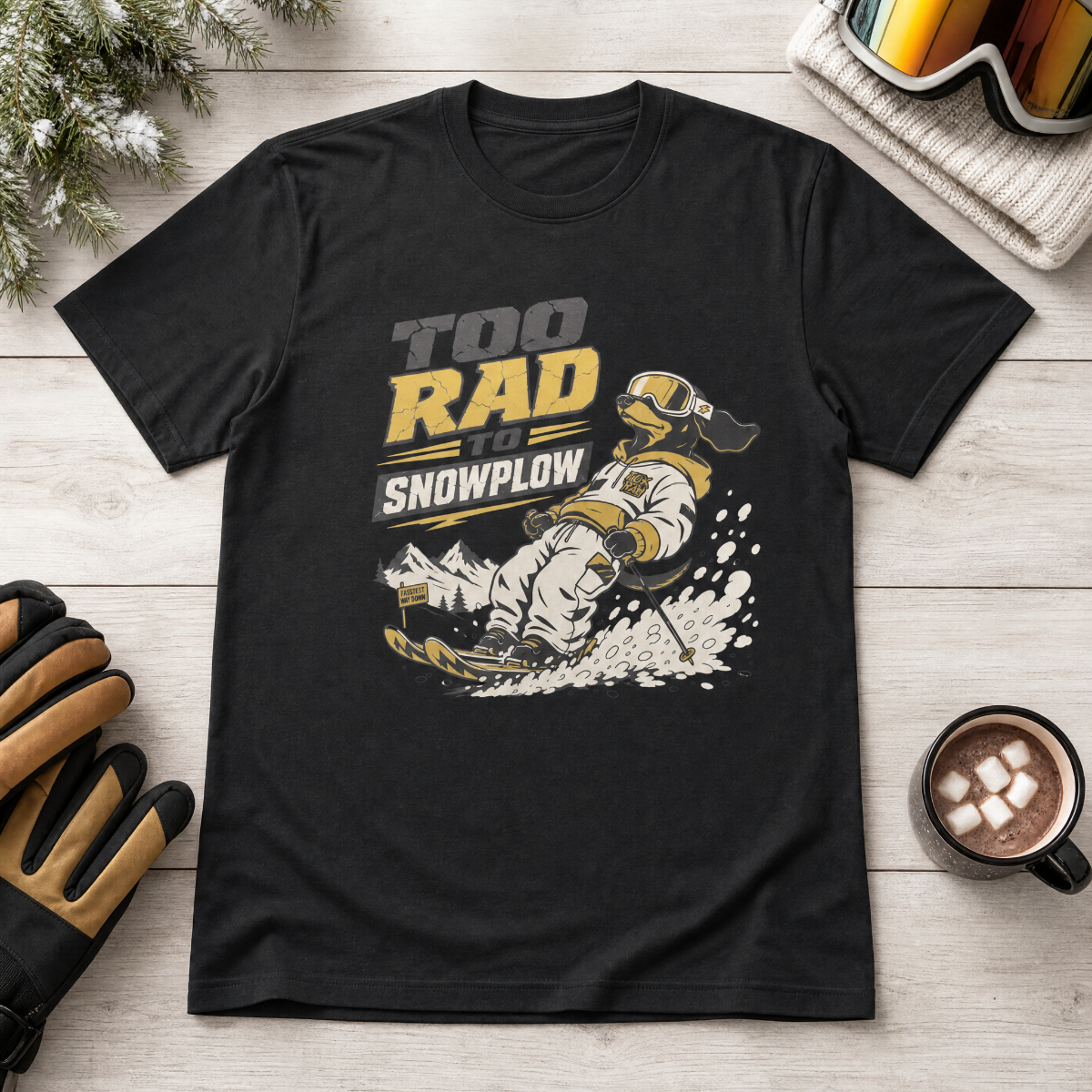 Black t-shirt with snowplow graphic and text on a wooden surface with gloves and hot chocolate.
