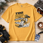 Yellow t-shirt with a graphic design of a person snowshoeing and text 'Too Rad to Snowplow' on a wooden surface with winter accessories.